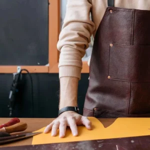 How to repair leather sofa showing a craftsman in a leather apron cutting material on a workbench for sofa restoration