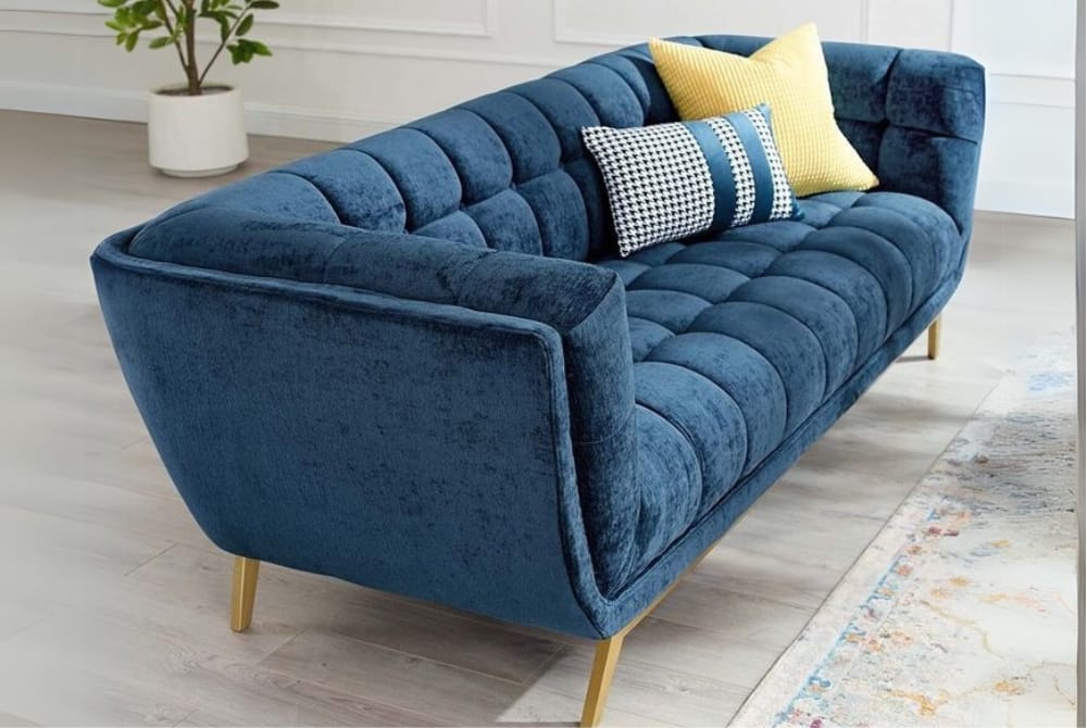 A Sofa with pillow in the room having velvet in blue colour