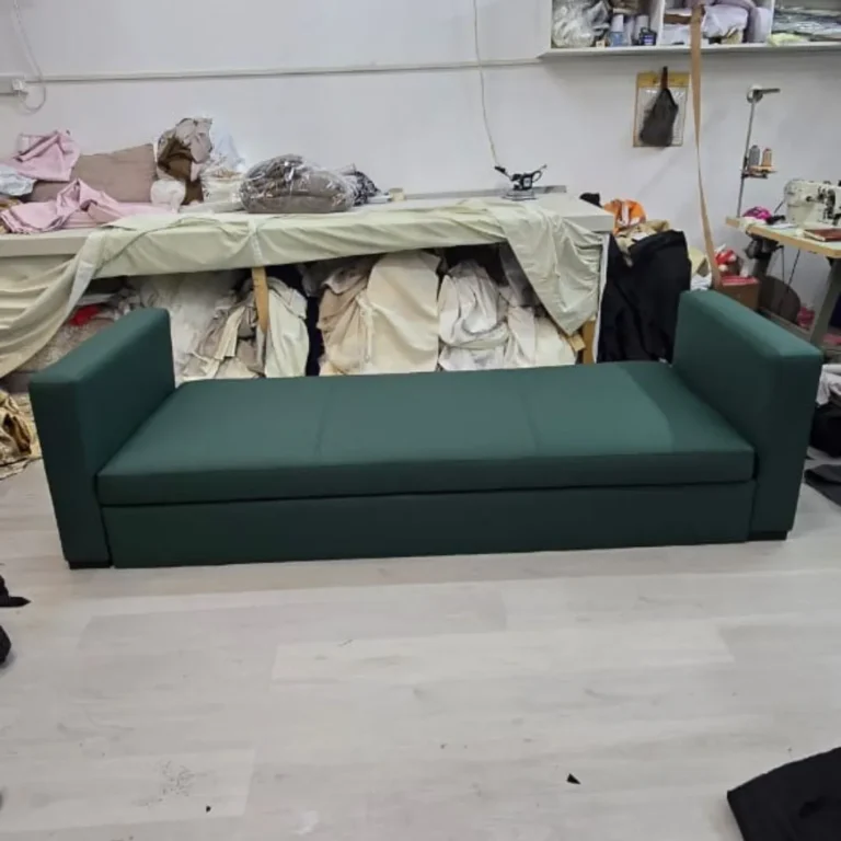 Sofa upholstery services in Dubai showing a craftsman smoothing leather material on a workbench during sofa restoration preparation