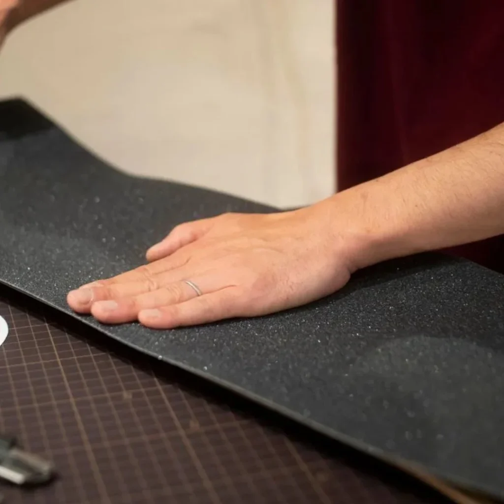 How to repair a faded leather sofa showing a person smoothing a black textured surface during the preparation stage before leather restoration