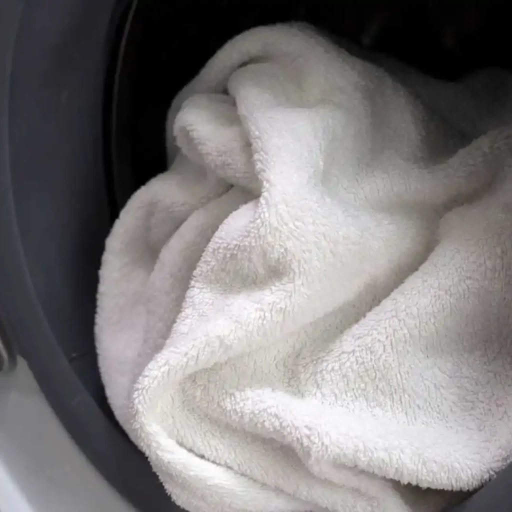How to dye sofa covers in washing machine showing a white sofa cover inside a washing machine during the dyeing cycle